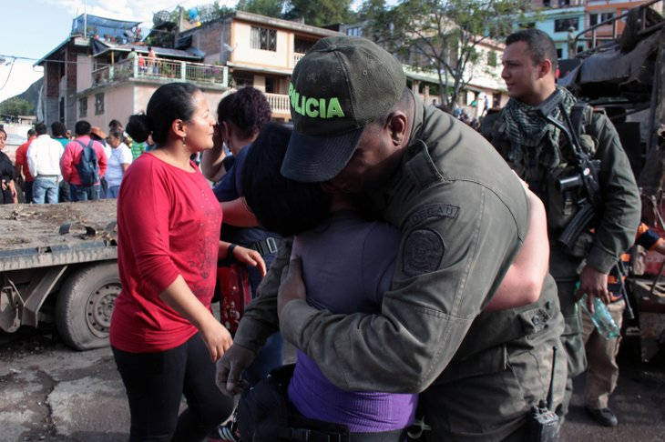 A police officer, who survived an attack on the police station of Inza, in Colombia's southern Cauca state, embraces a relatives in front of the post, Saturday, Dec. 7, 2013. The Colombian Army said that five members of the military, two civilians and a police officer were killed after rebels of the Revolutionary Armed Forces of Colombia, FARC, threw artisanal mortar at the post from a truck, destroying that and several other buildings. (AP Photo/Juan Bautista Diaz) 